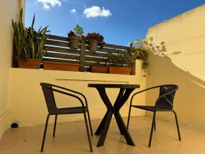 two chairs and a table on a balcony with plants at Private One Bedroom Apartment close to Airport in Luqa in Luqa