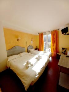 two beds in a hotel room with orange curtains at Hotel Restaurant Le Costabonne in Prats-de-Mollo-la-Preste