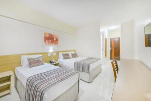 a hotel room with two beds and a desk at Hotel Nacional Inn Piracicaba in Piracicaba