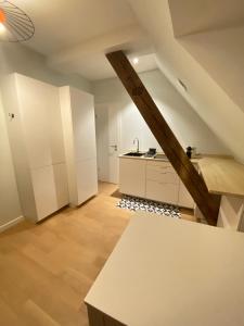 una cocina en el ático con armarios blancos y una mesa en Les toits de Gutenberg, en Estrasburgo
