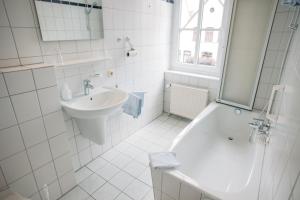 a white bathroom with a sink and a bath tub at Hotel Zum König von Griechenland in Ovelgönne