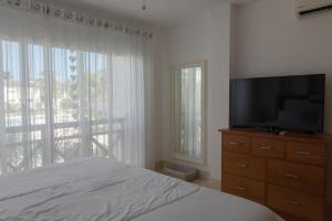 a bedroom with a bed and a flat screen tv at Riviera Azul Playa Dorada in San Felipe de Puerto Plata