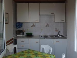 eine Küche mit weißen Schränken, einem Tisch und einem Waschbecken in der Unterkunft Apartman Nena in Klenovica