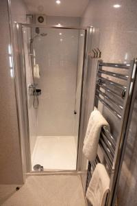 a shower with a glass door and towels in a bathroom at Scandinavian Village Ltd in Aviemore