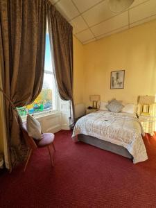 a bedroom with a bed and a chair and a window at Morehampton Townhouse in Dublin