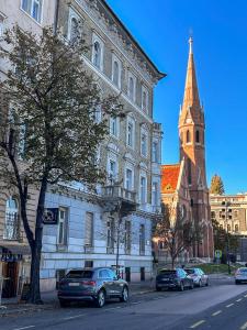 Pd Residence في بودابست: كنيسة فيها برج وسيارات تقف امام مبنى