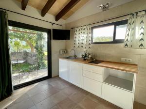 a kitchen with white cabinets and a large window at Finca Hotel Son Pont in Puigpunyent