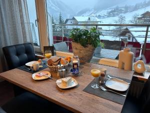 una mesa con comida y vasos de zumo de naranja en Appartement 412 Kunners Oostenrijk en Mittelberg