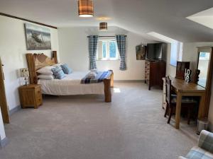 a bedroom with a bed and a table and a desk at Bedlwyncoch Farmhouse in Brecon