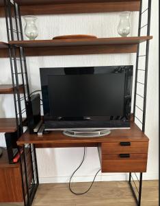 TV sentada en una mesa de madera en un estante en Appartement 3 pièces avec parking couvert gratuit., en Le Pré-Saint-Gervais