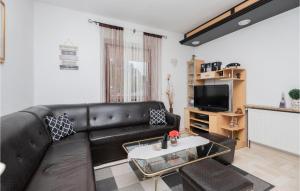 a living room with a black leather couch and a tv at Awesome Home In Mijaca With Kitchen 