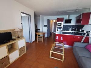 salon z kanapą oraz kuchnia z czerwonymi szafkami w obiekcie 176 Indes Galantes G91 w Cap d'Agde