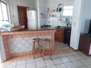 une cuisine avec deux tabourets en bois à un comptoir dans l'établissement Cobertura com terraço e churrasqueira, à Florianópolis