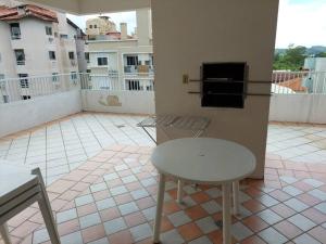 d'une table et d'une chaise blanches sur un balcon. dans l'établissement Cobertura com terraço e churrasqueira, à Florianópolis