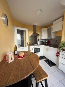 una cocina con una mesa de madera y una botella de vino en Le nid des Pruniers - F2 au calme - parking privé, en Sélestat