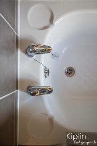 lavabo blanco con dos grifos cromados en Surrey Lodge en Richmond