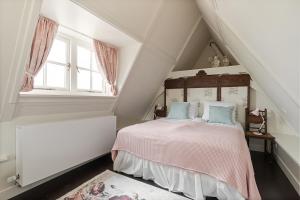 a white attic bedroom with a bed with pink sheets at Boutique Hotel Jongwijs Westzaan in Westzaan