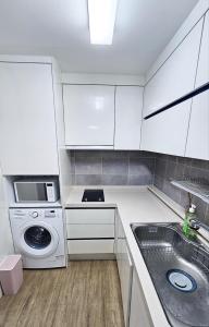 cocina blanca con fregadero y lavadora en Modern Terrace, en Jeju