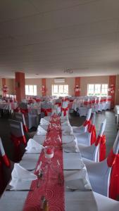 a long dining room with white tables and red and white chairs at LOGIS Le Pot D'Etain in Holnon