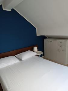 - une chambre avec un lit blanc et un mur bleu dans l'établissement Le cocon, à Gochenée