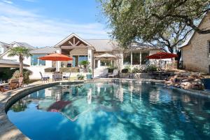 a swimming pool with umbrellas in front of a house at Stunning Lakefront Retreat Pool Boat Lift Spectacular Views in Horseshoe Bay