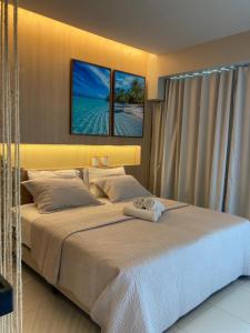 a bedroom with a large bed with two pictures on the wall at Mana Beach Experience - 62m2 - 2 quartos - 1 Suite - com opcao de terreo tipo studio, 30m2 - Praia de Muro Alto in Porto De Galinhas