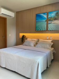 a bedroom with a large white bed with two pillows at Mana Beach Experience - 62m2 - 2 quartos - 1 Suite - com opcao de terreo tipo studio, 30m2 - Praia de Muro Alto in Porto De Galinhas