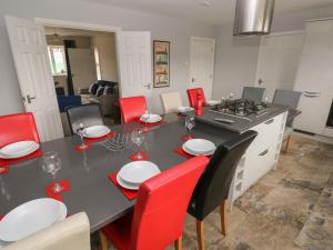a kitchen with a dining table and red chairs at Llygad Y Lleuad Moon in Burry Port