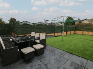 eine Terrasse mit einem Tisch und Stühlen sowie einem Garten in der Unterkunft Llygad Y Lleuad Moon in Burry Port
