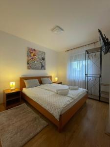 a bedroom with a bed with two lamps and a window at Kuća za odmor Saturnus in Karanac