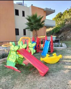 a playground with colorful slides and a palm tree at Hotel Jaho in Kavajë