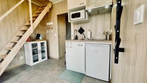 a kitchen with a white refrigerator and a staircase at Tiny house proche de Morgat in Crozon