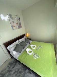 a bed with a green blanket and two towels on it at Brenthill Baguio condo unit near SM baguio in Baguio