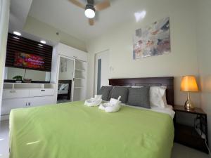 a bedroom with a green bed with two stuffed animals on it at Brenthill Baguio condo unit near SM baguio in Baguio
