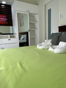 a bedroom with a green bed with towels on it at Brenthill Baguio condo unit near SM baguio in Baguio