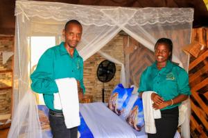 two people standing in front of a bed at Amanya Camp 1 Double -Bed Tiger in Amboseli in Amboseli