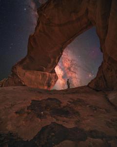 a person standing inside of a rock arch at night at Wadi Rum desert Mohammed in Wadi Rum