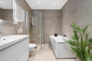 uma casa de banho com uma banheira branca, um WC e um lavatório. em Enter City Apartment Hotel em Tromsø