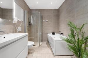 a bathroom with a white tub and a toilet and a sink at Enter City Apartment Hotel in Tromsø