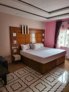 ein Schlafzimmer mit einem großen Bett in einem rosa Zimmer in der Unterkunft M View Hotel in Benin City