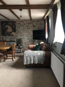 a living room with a couch and a brick wall at Llysfaen Cottage in Brecon