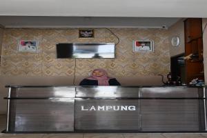 a woman is standing behind a counter in a waiting room at Rimbawan Guest House in Lampung