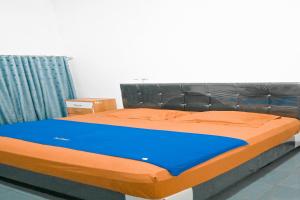 a bedroom with a bed with blue and orange sheets at Rimbawan Guest House in Lampung