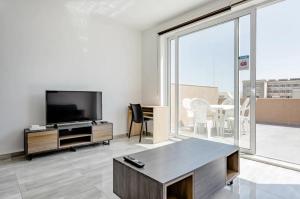 a living room with a tv and a large window at F12 Modern and Bright Apartment in Malta in Msida