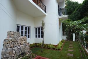 ein weißes Haus mit einer Steinmauer in der Unterkunft Palace Hostel by Borrbo in Mysore