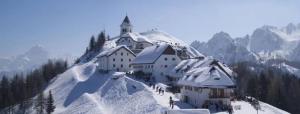 a building on top of a snow covered mountain at Hotel Tarvis in Tarvisio