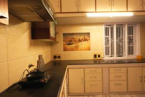 a kitchen with white cabinets and a black counter top at Palace Hostel by Borrbo in Mysore
