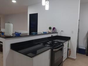 cocina con encimera negra y fogones en Relajate en un hermoso apartamento Duplex cerca de la playa y piscina en Playa Blanca, Farallon, en Río Hato