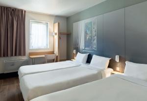 Habitación de hotel con 2 camas y mesa en B&B HOTEL Evry Lisses 1 en Lisses
