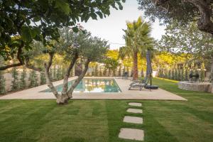 a garden with a swimming pool and a tree at escape to sounio cape in Panayía